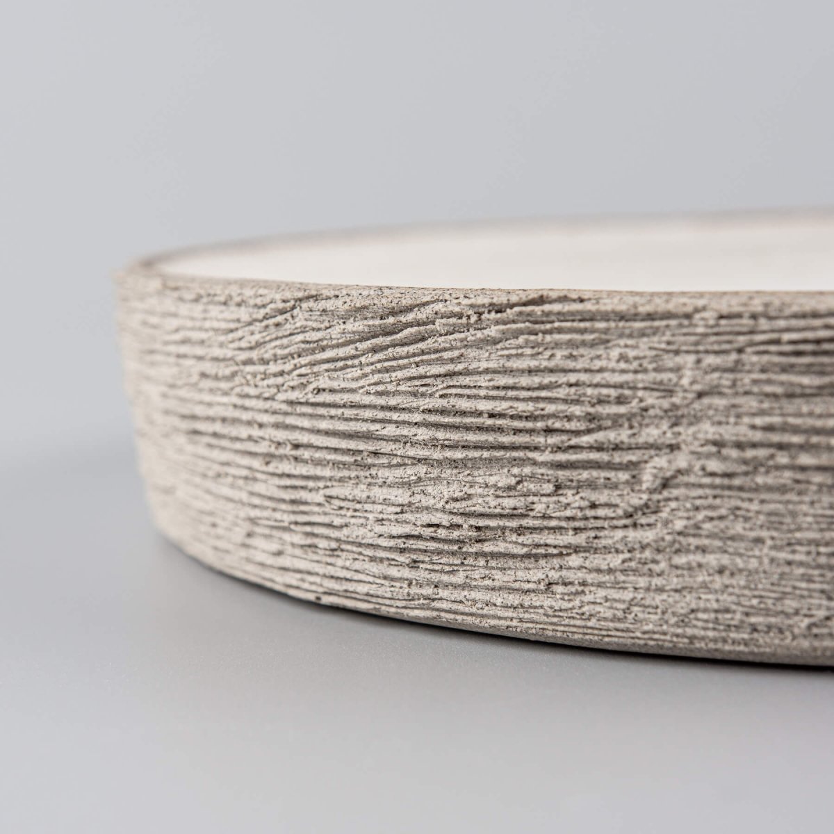 Close-up of artisan ceramic plate edge showcasing hand-carved textured stoneware craftsmanship.