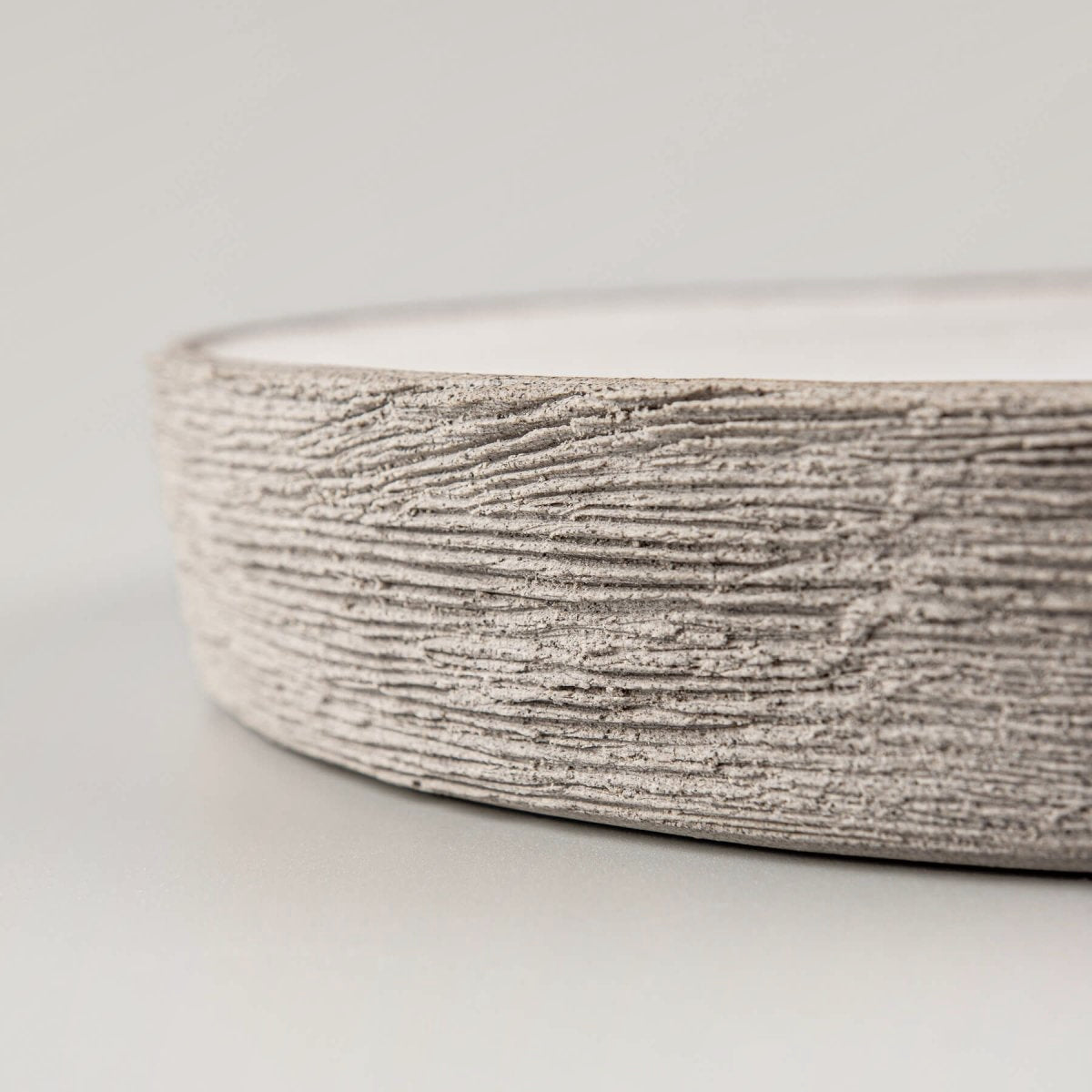 Close-up of artisan ceramic plate edge showcasing hand-carved textured stoneware craftsmanship.