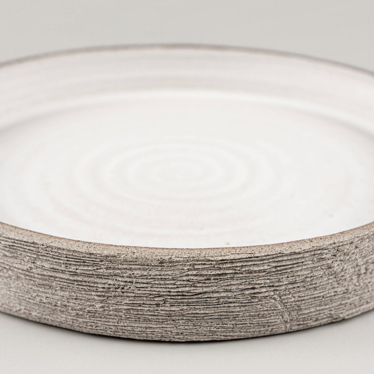 Premium handmade ceramic plate with smooth interior and raw clay exterior for luxury table settings.