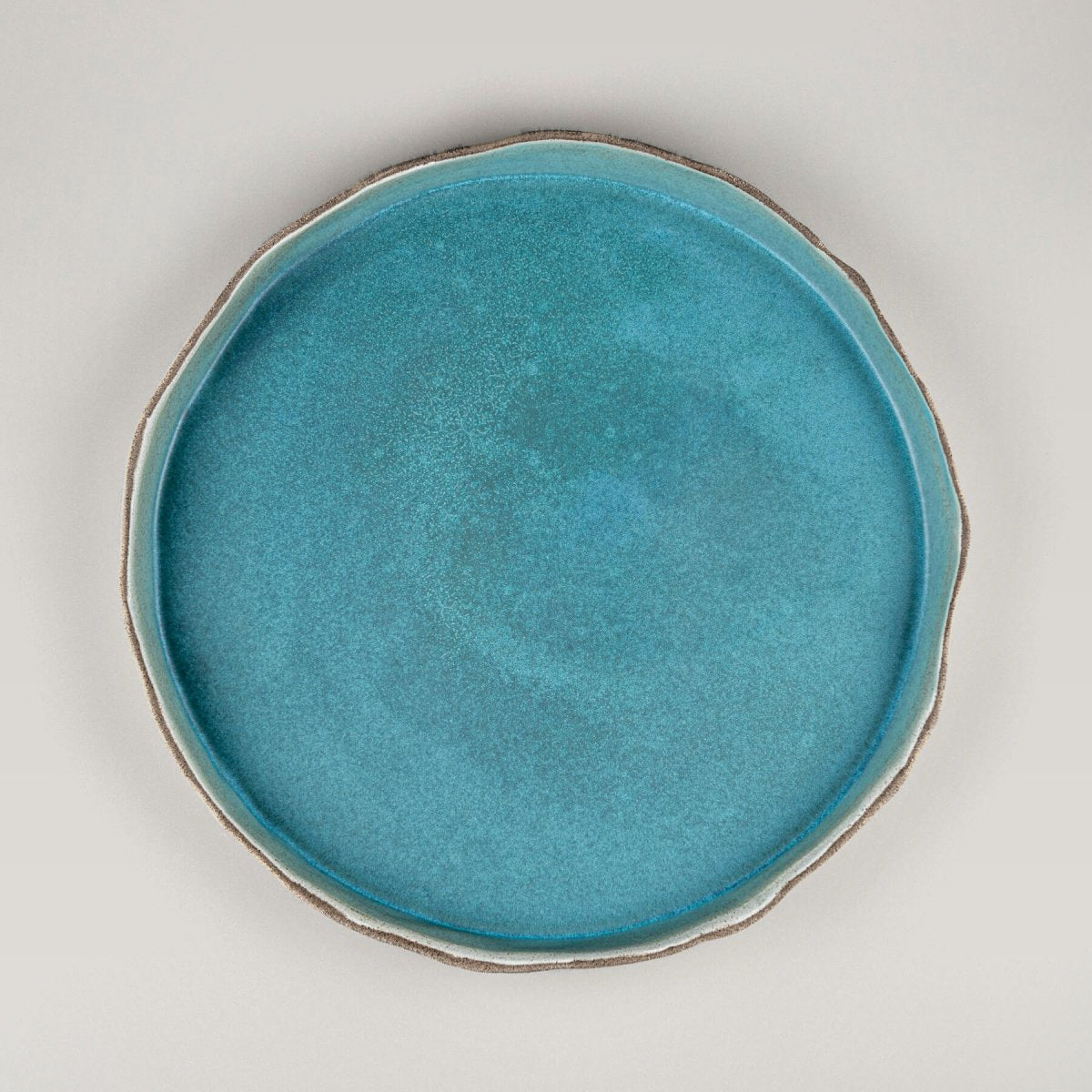 Handmade dinner plate in matte turquoise with wave-like white edges for fine dining and luxury tableware.