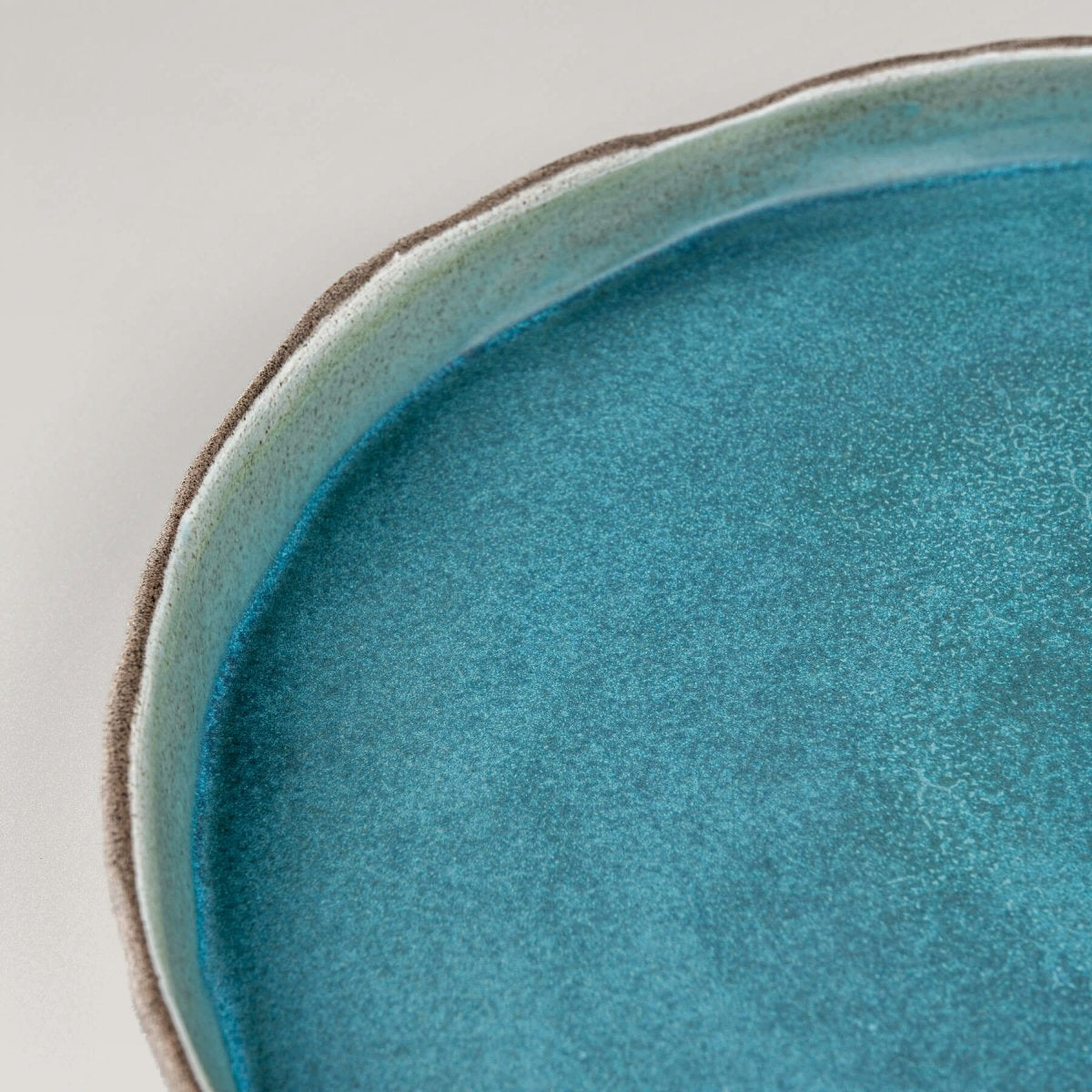 Matte turquoise handmade dinner plate showcasing smooth interior glaze and natural clay contrast.