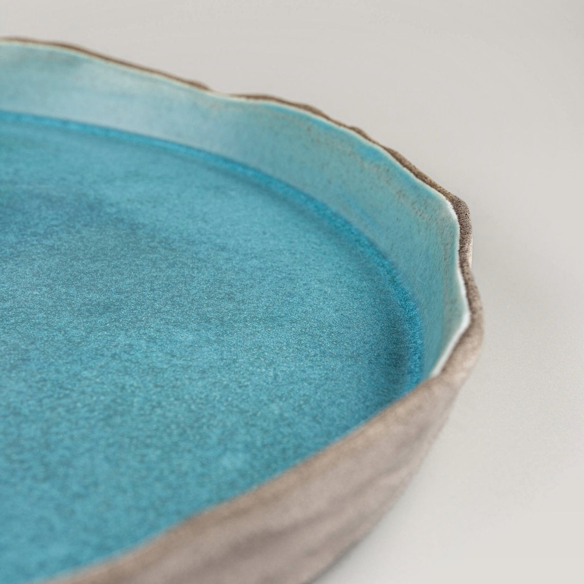 Elegant handmade dinner plate in turquoise glaze with flat base and refined craftsmanship.