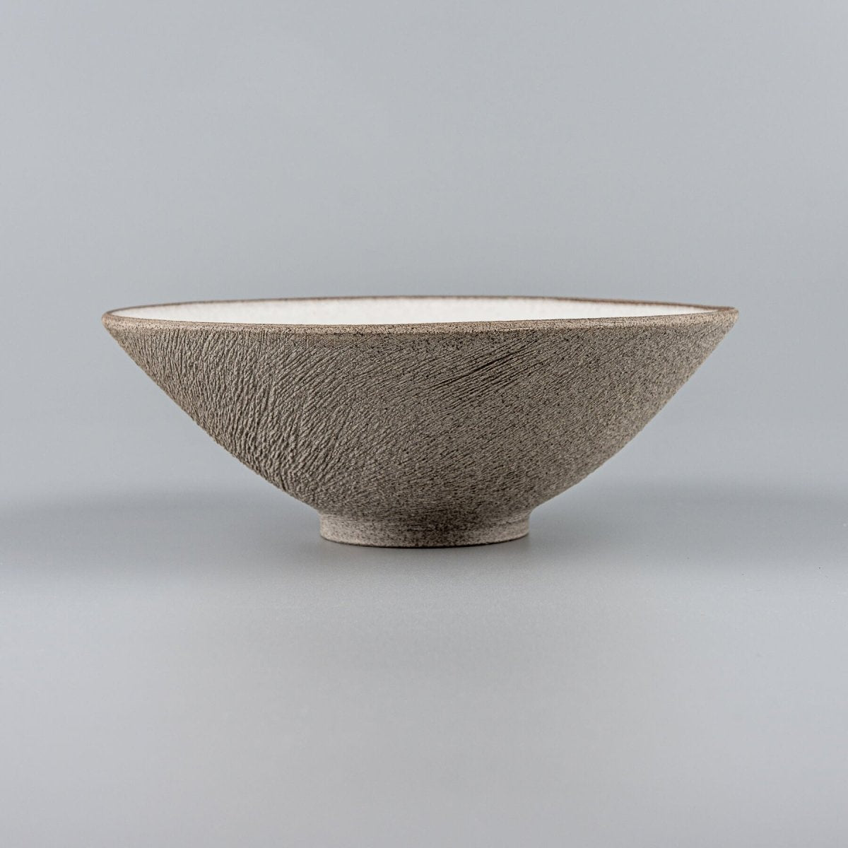 Hand-thrown artisanal bowl showcasing fine beveled lines and dark stoneware texture.