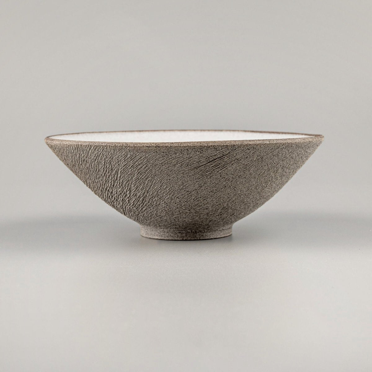 Hand-thrown artisanal bowl showcasing fine beveled lines and dark stoneware texture.