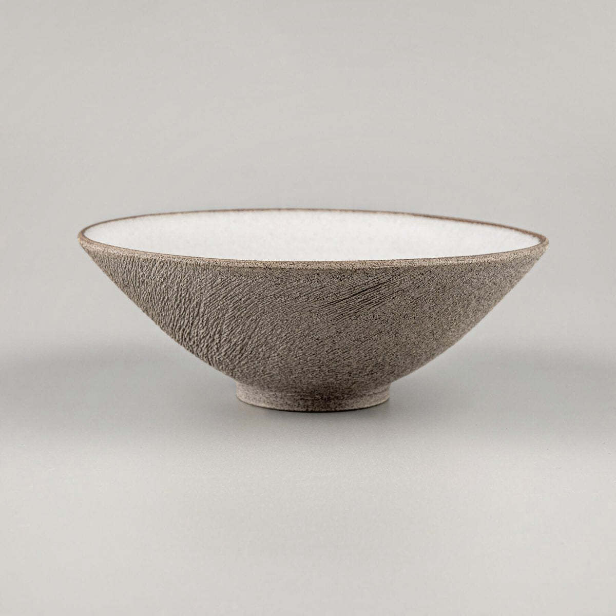 Side profile of conical stoneware bowl with textured surface and elegant form.