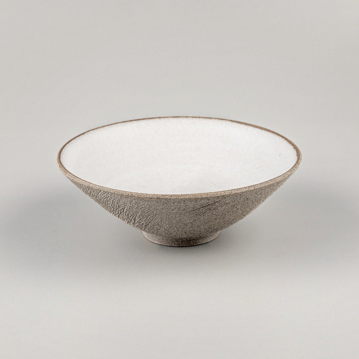 Ceramic serving bowl with minimalist glaze inside and handcrafted unglazed outside surface.