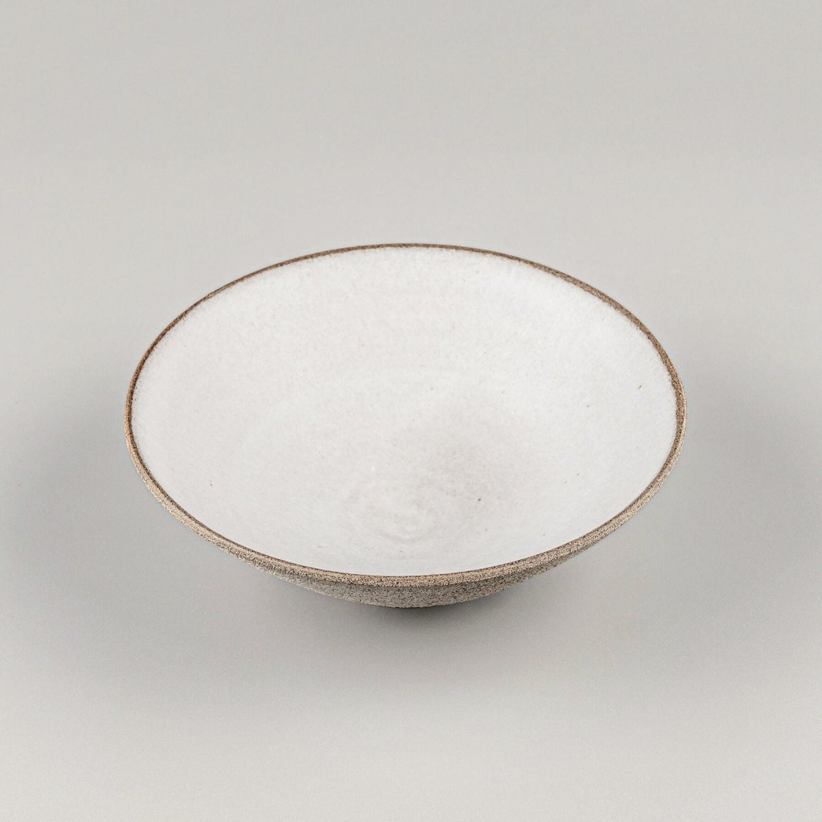 Elevated view of fine dining ceramic bowl with wide opening and footed base.