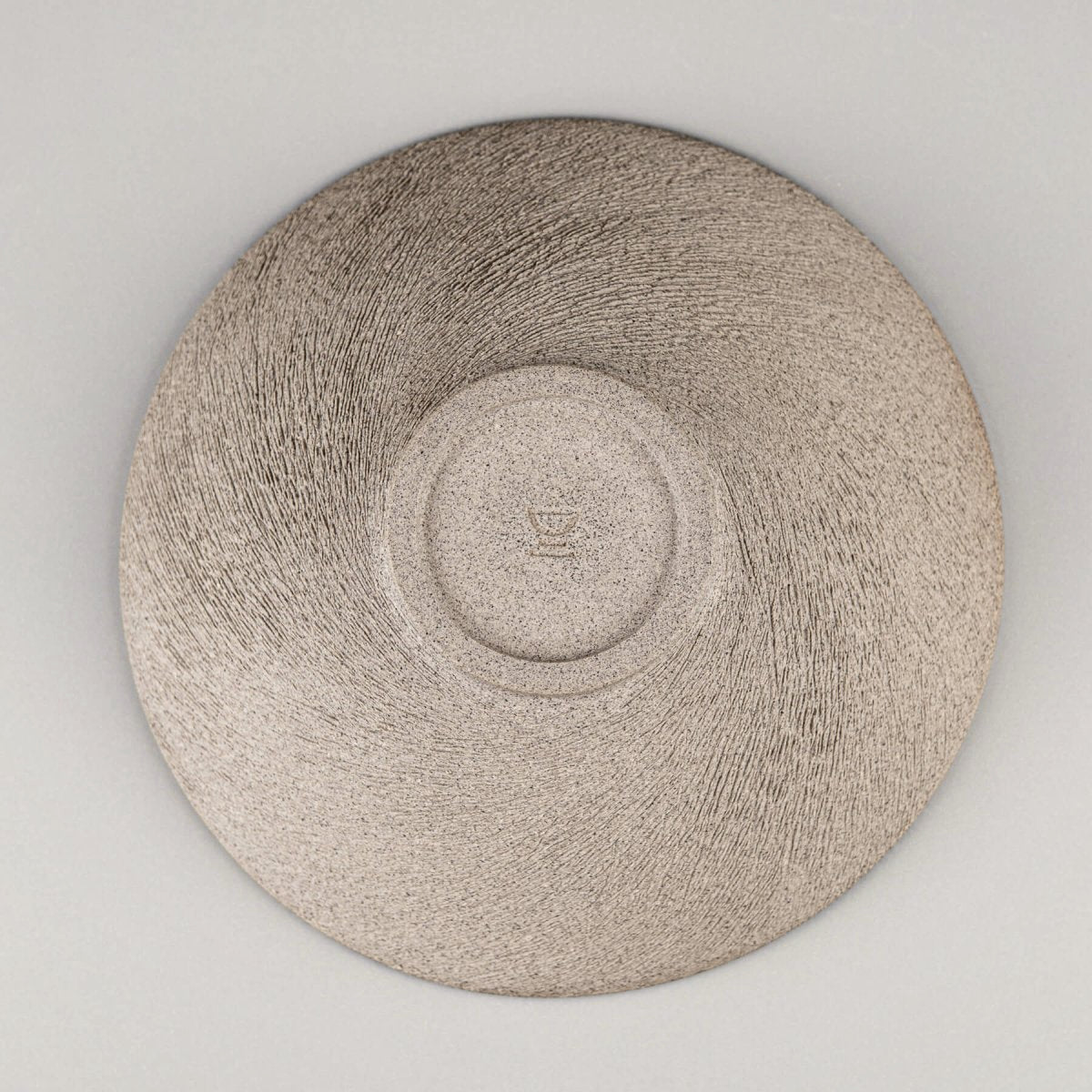 Underside of handmade bowl showing raw clay texture and potter’s signature.