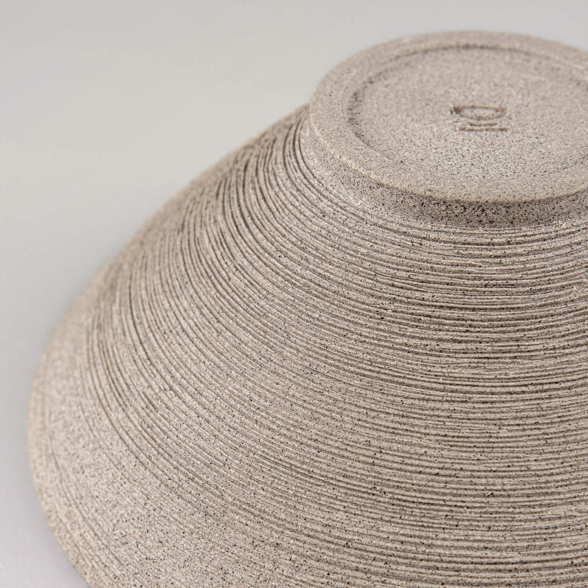 Close-up of rough carved stoneware texture on artisanal ceramic bowl.