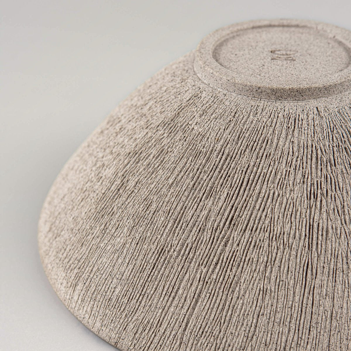 Detail of hand-carved lines on unglazed exterior of pottery bowl.
