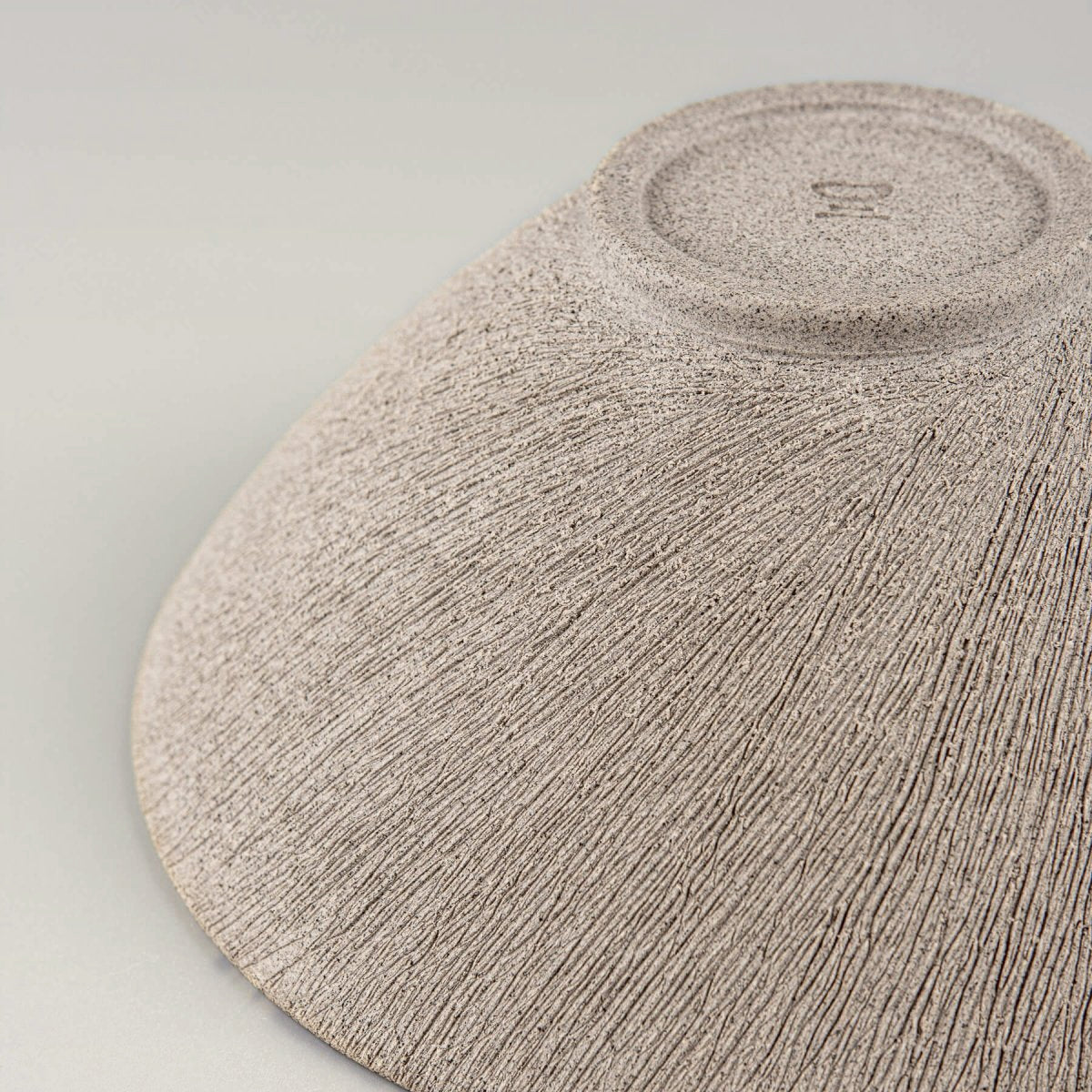 Close-up of exterior texture highlighting the handcrafted carving on raw clay.