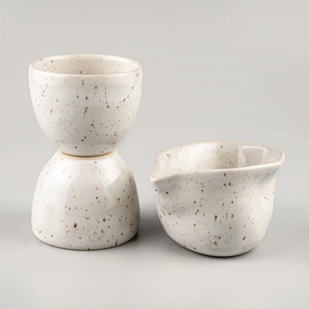 Minimalist stoneware coffee cups in ivory glaze with speckled design for interior design and culinary presentation.