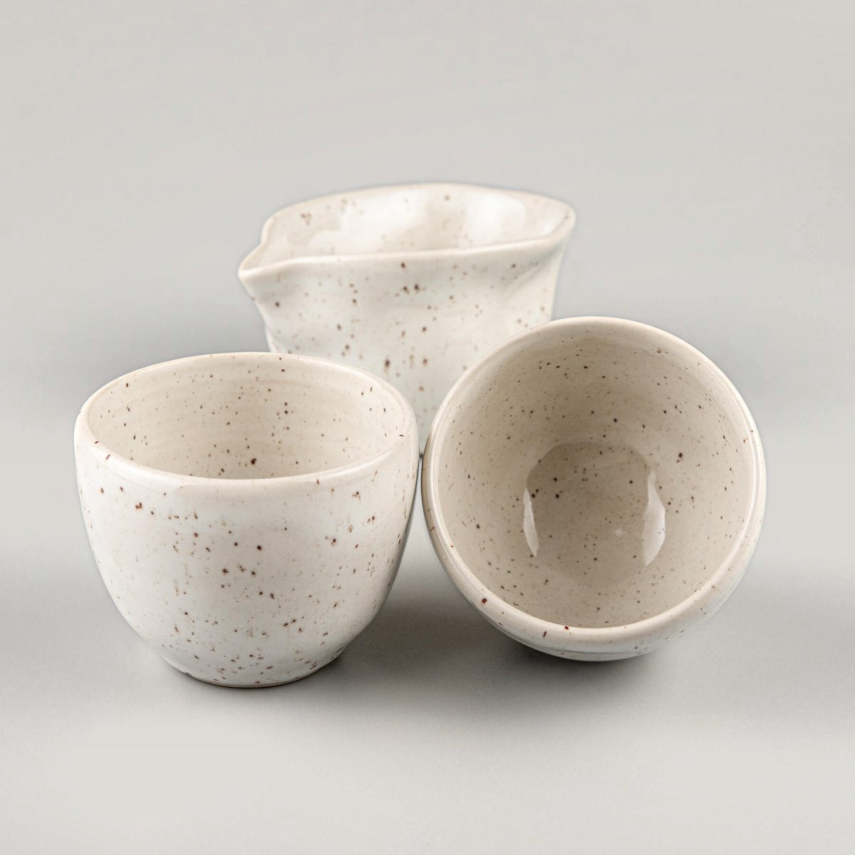 Handmade pottery set featuring coffee cups and a pitcher, crafted for fine dining and collectible tableware.