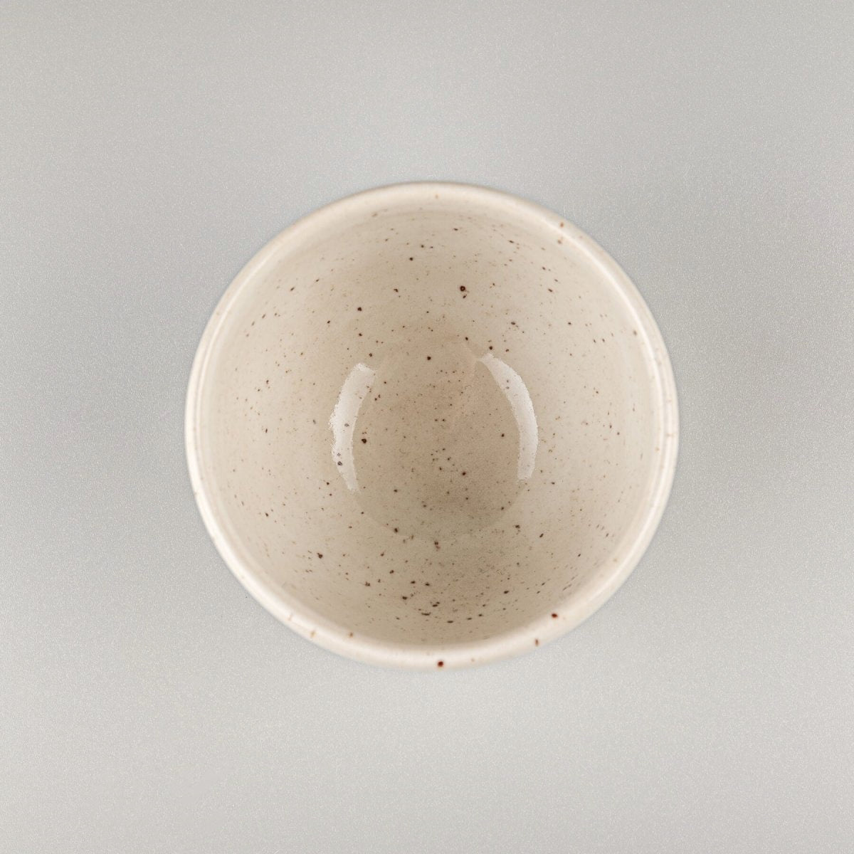 Top view of a handcrafted coffee cup with glossy ivory glaze, perfect for culinary presentation.