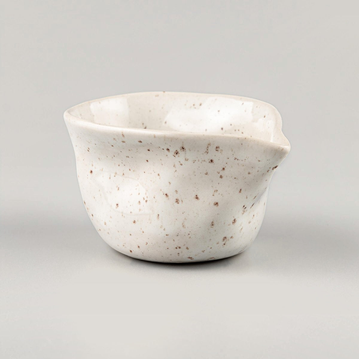 Organic-shaped milk pitcher in ivory-glazed stoneware, handmade for serving coffee and tea with elegance.