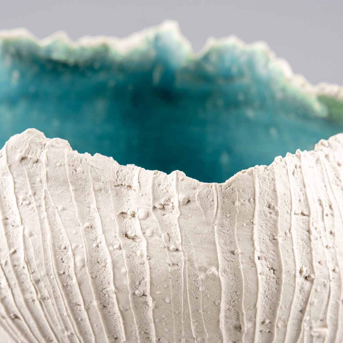Stoneware vase with irregular rim and turquoise ocean-inspired glaze, perfect for a fine dining centerpiece.