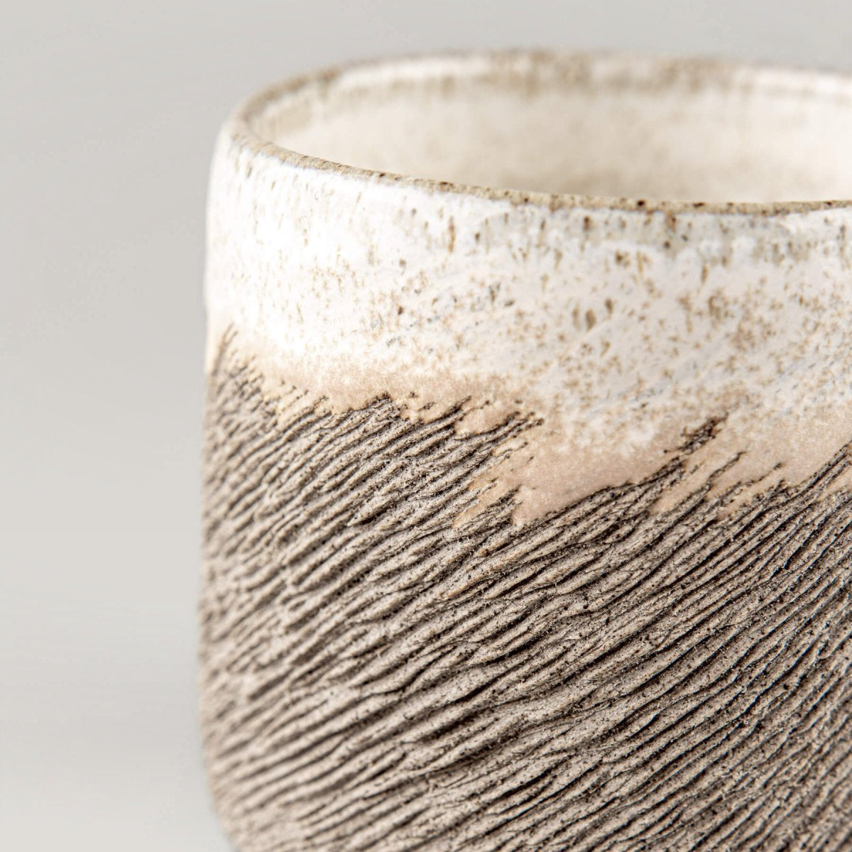 Close-up of textured stoneware coffee cup highlighting natural clay finish and handmade craftsmanship for interior design.