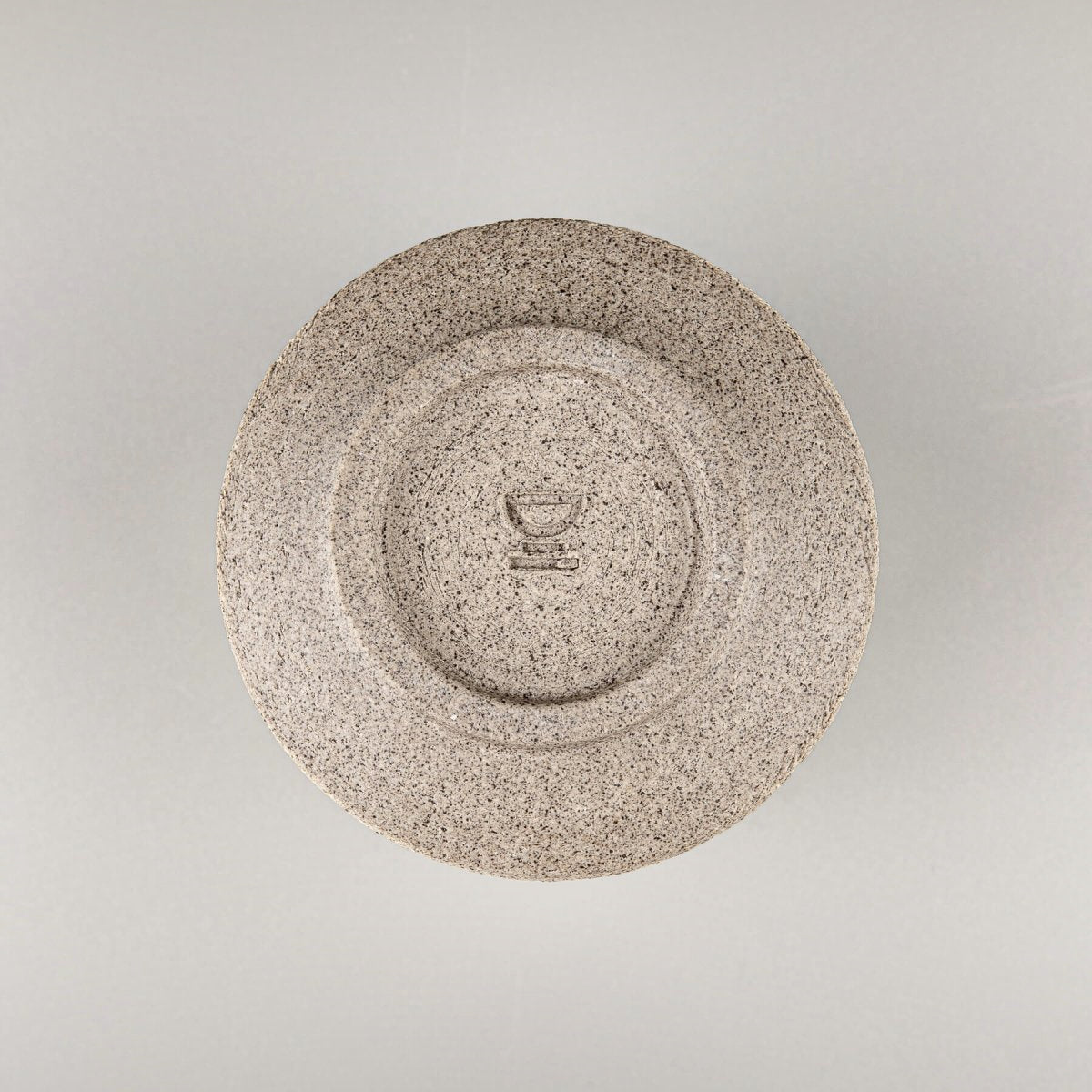 Base of handmade stoneware coffee cup with carved foot and natural clay finish, reflecting artisanal craftsmanship.
