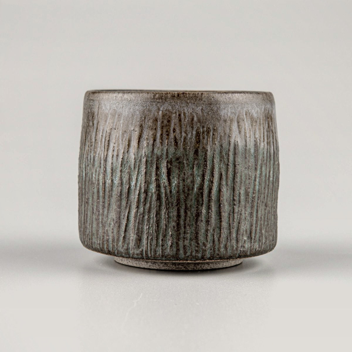 Handcrafted stoneware coffee cups with dark matte glaze and carved texture, perfect for fine dining tableware.