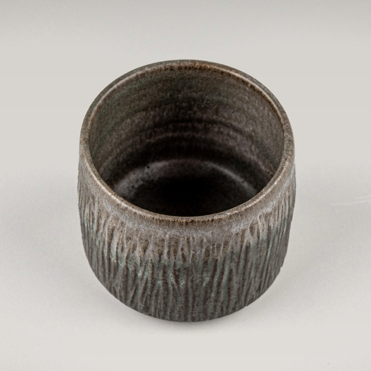 Dark stoneware coffee cups with flat edges and carved exterior, suitable for restaurants and housewarming gifts.