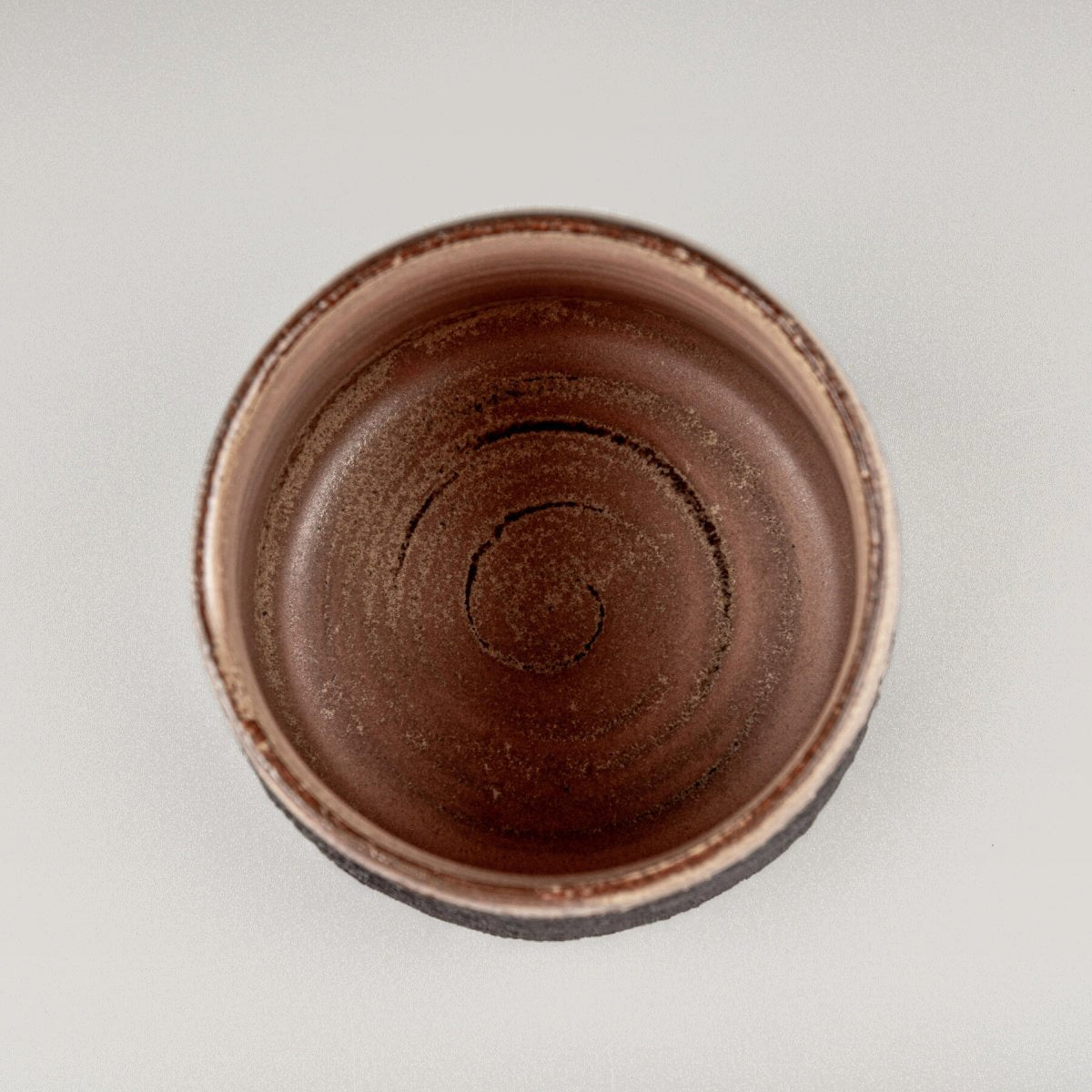 Top view of artisanal pottery mug with smooth glazed interior and textured stoneware exterior for culinary use.