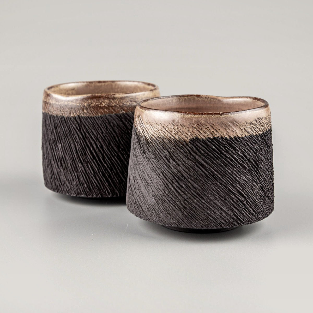 Handcrafted pottery mugs with black stoneware clay and carved textured design for fine dining and home decor.