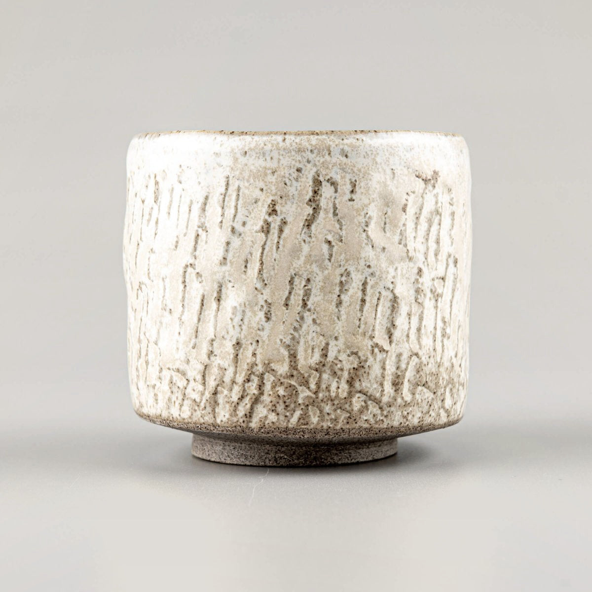 Rustic ceramic espresso cup with carved surface and minimal design for tableware and decor.
