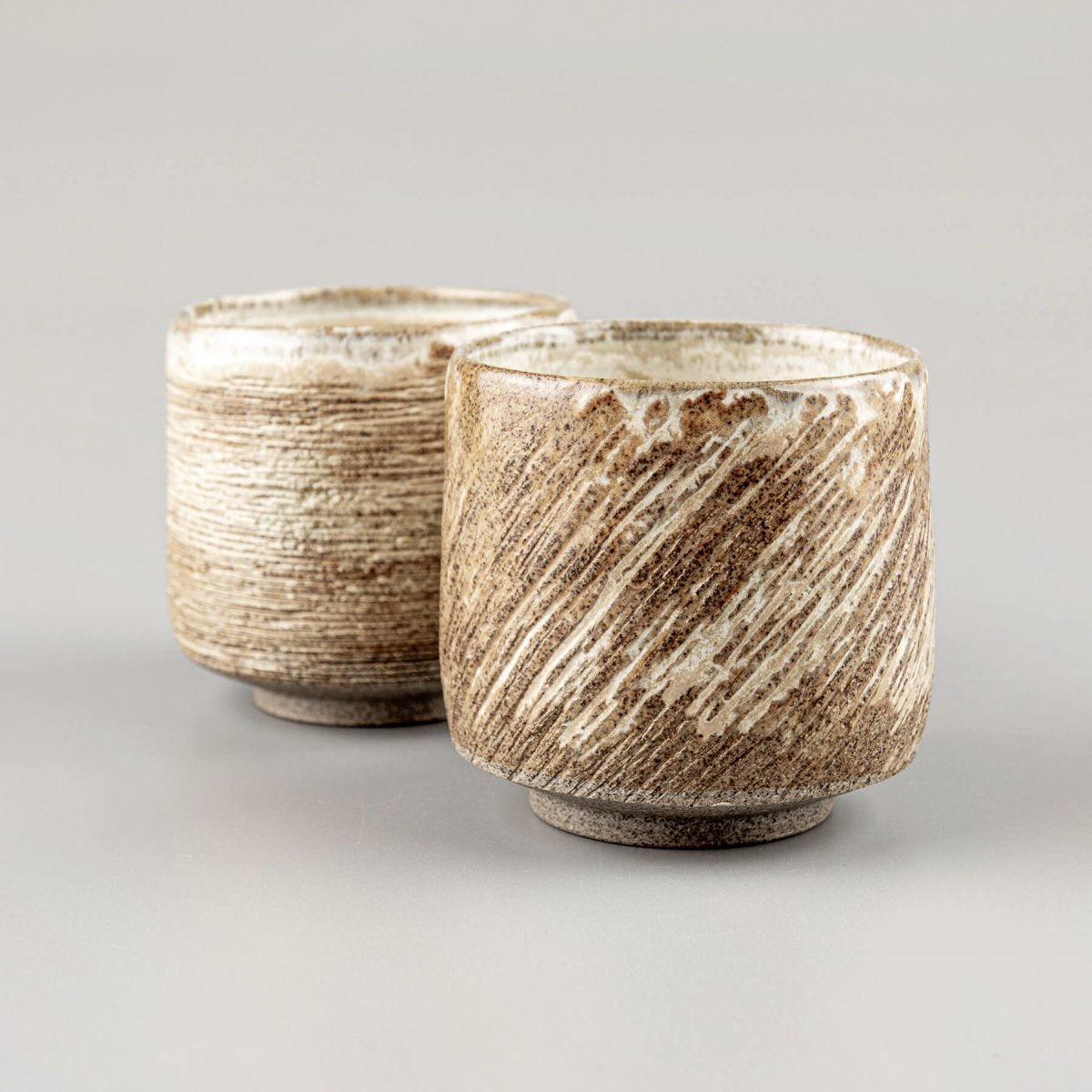 Handmade ceramic mugs with carved diagonal texture and matte glaze for home and restaurant use.