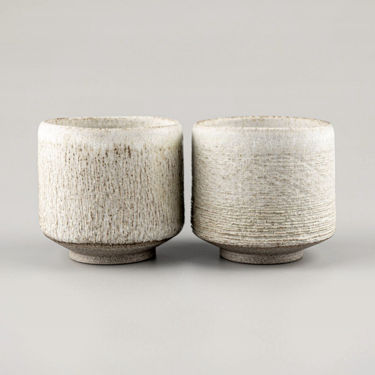 Elegant ceramic mugs with textured carving, perfect for fine dining and handmade decor.