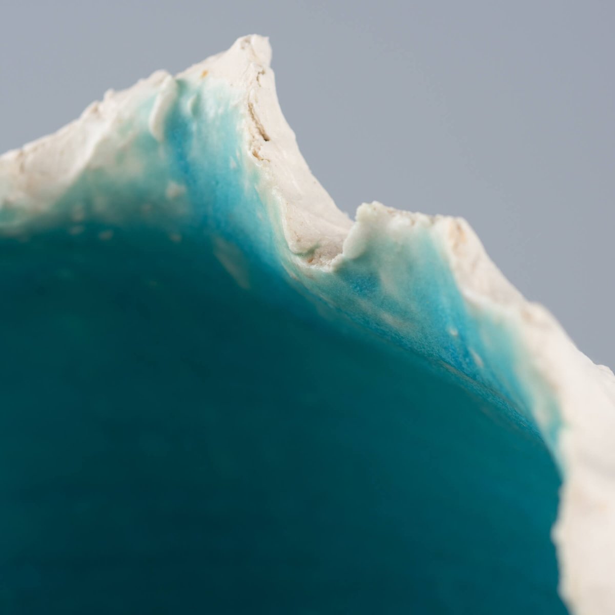 Modern stoneware vase featuring a sculptural white exterior and ocean-depth turquoise glaze, designed for private collectors.