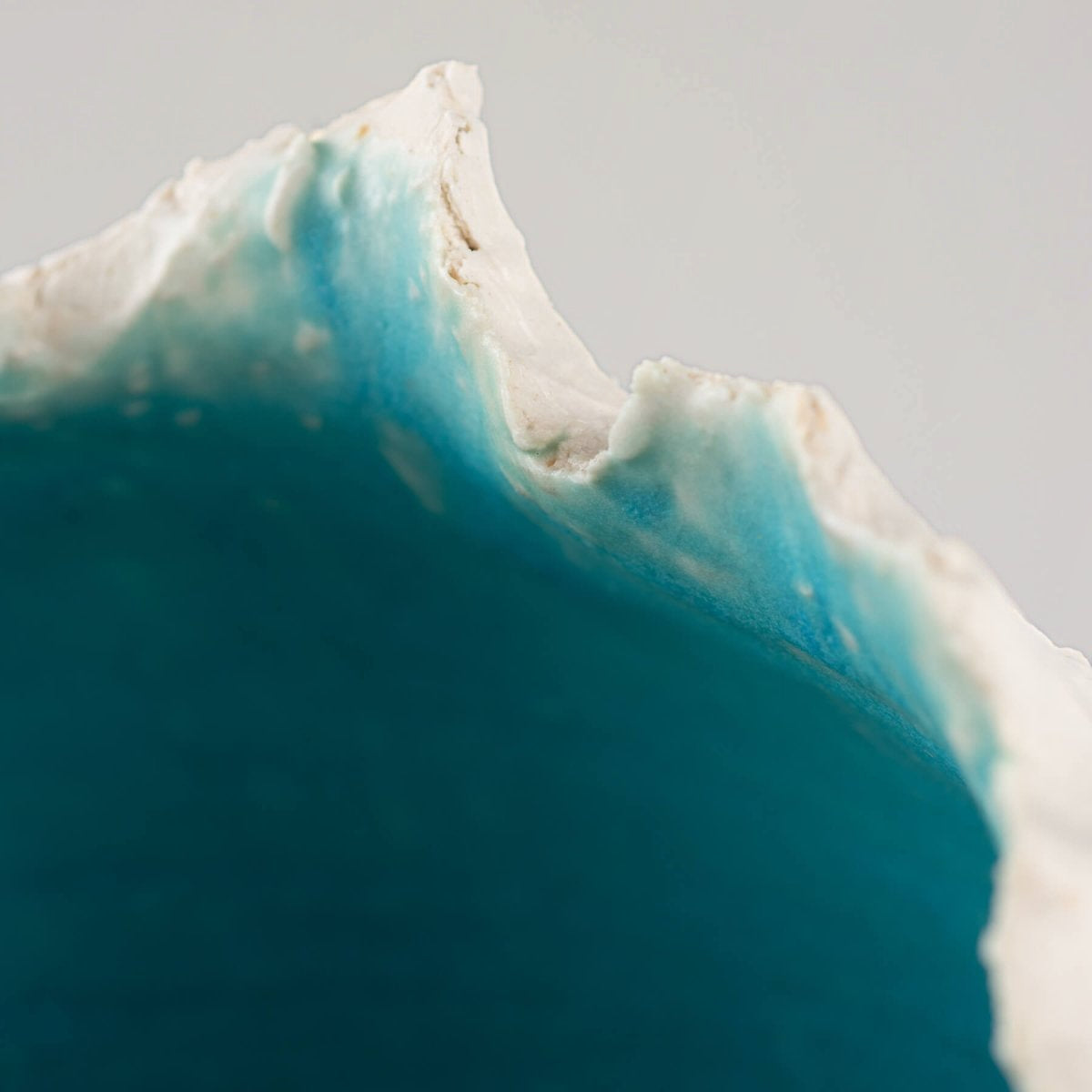 Modern stoneware vase featuring a sculptural white exterior and ocean-depth turquoise glaze, designed for private collectors.