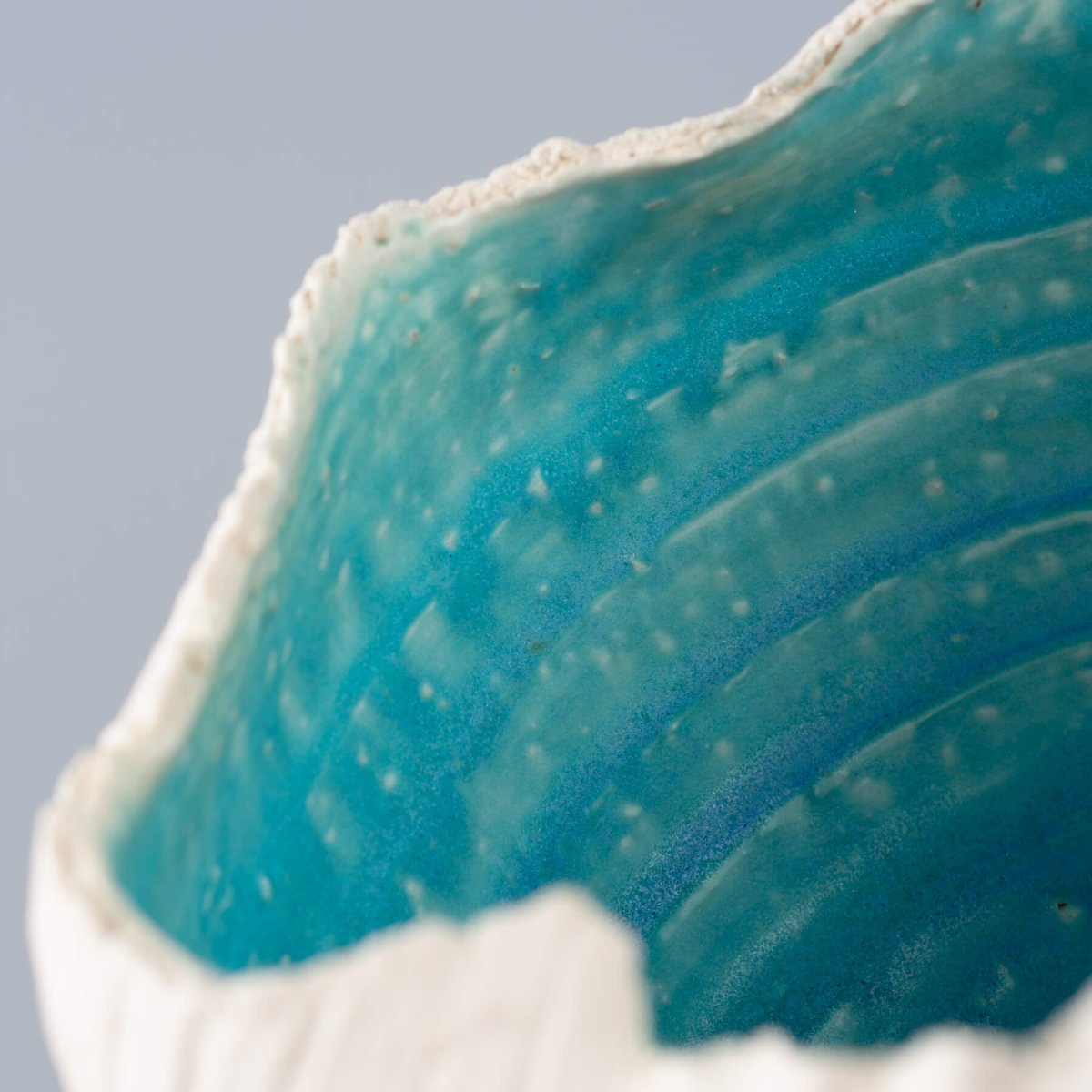 Handmade stoneware vase inspired by seashells and ocean waves, featuring a turquoise finish, a limited-edition piece of decor