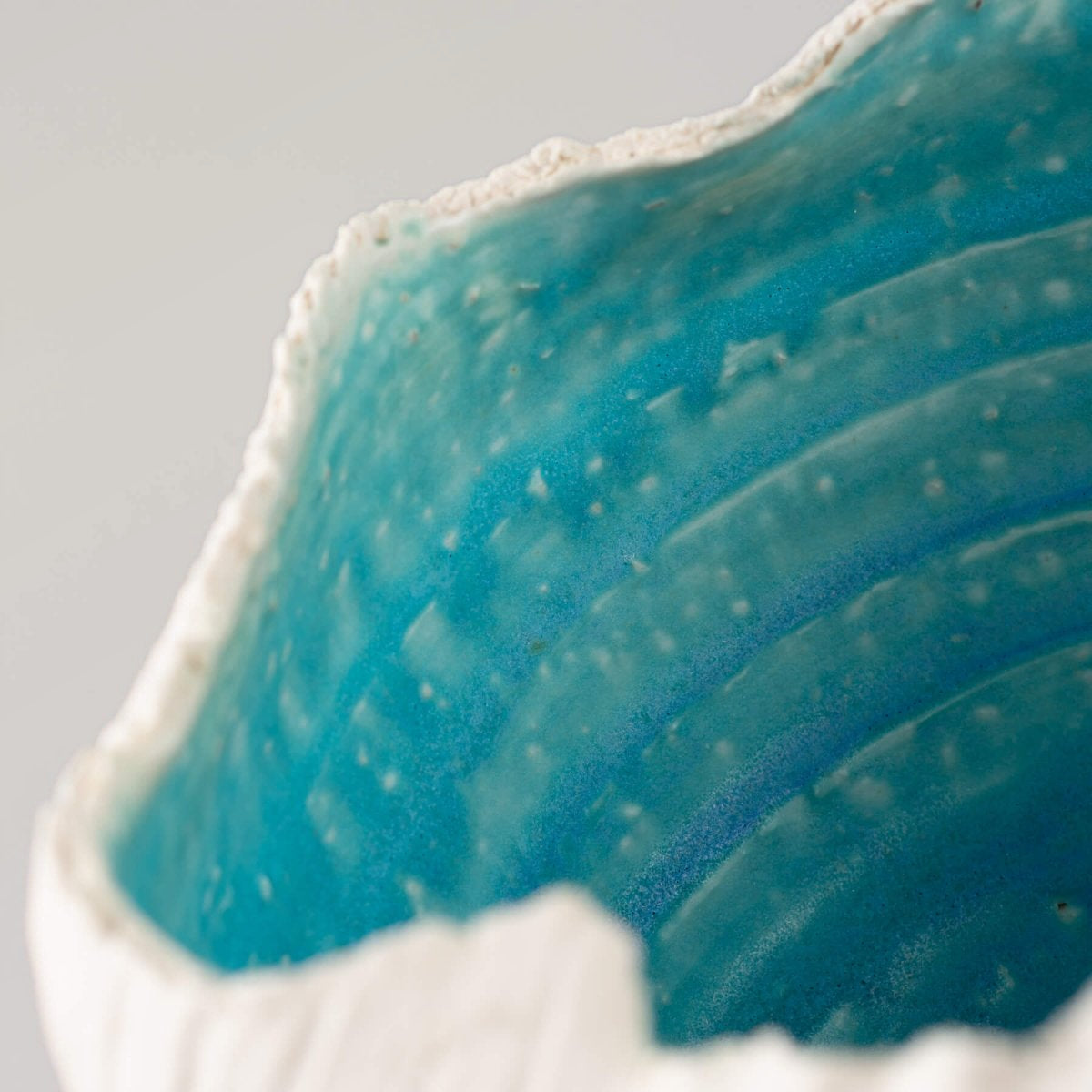 Handmade stoneware vase inspired by seashells and ocean waves, featuring a turquoise finish, a limited-edition piece of decor