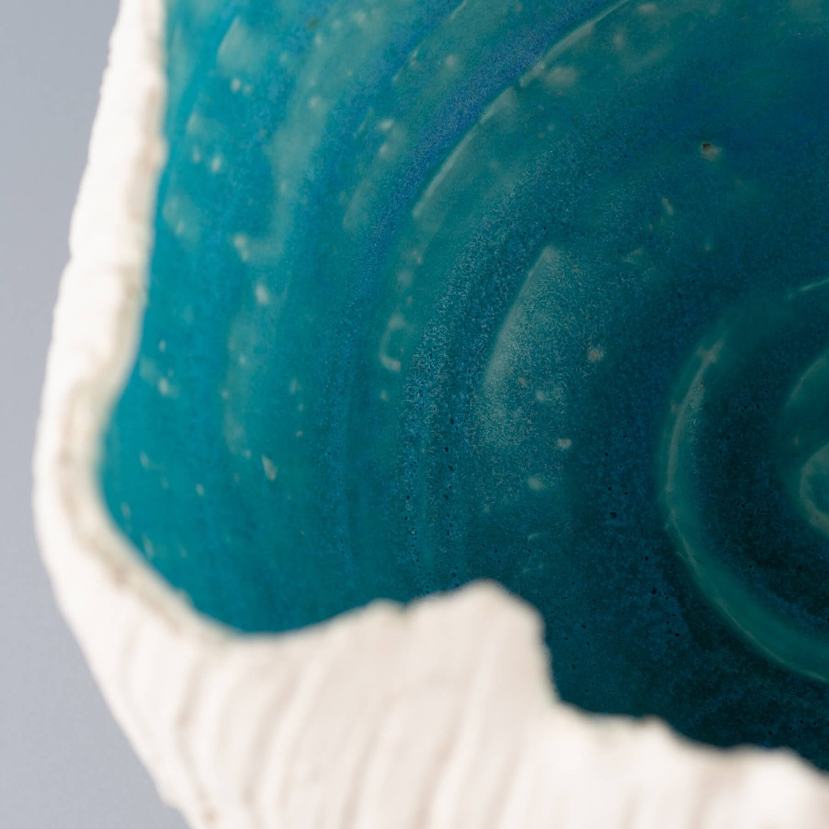 Detail of a stoneware vase with an organic rim and turquoise interior, perfect for boutique hotels and fine dining design.