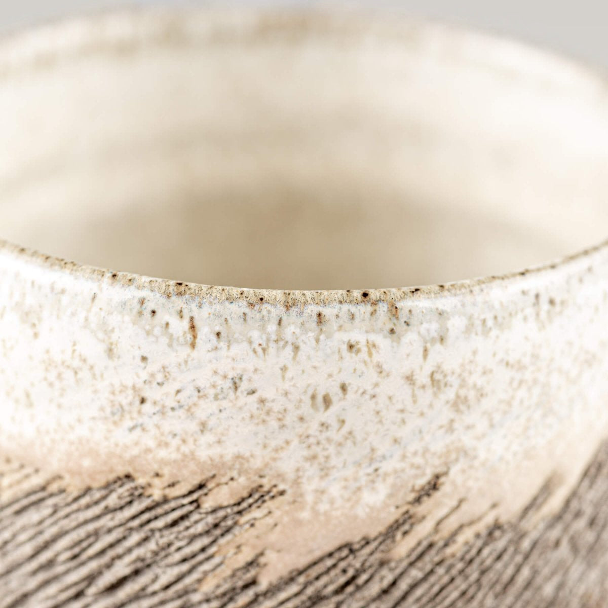 Detail of artisanal stoneware coffee cup exterior showing unique tactile carving and ceramic artistry for tableware.