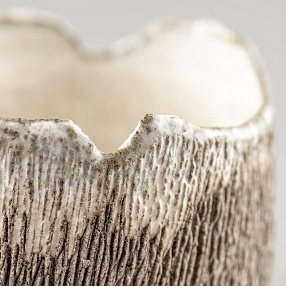 Detail of irregular rim stoneware coffee cup highlighting artisan craftsmanship.