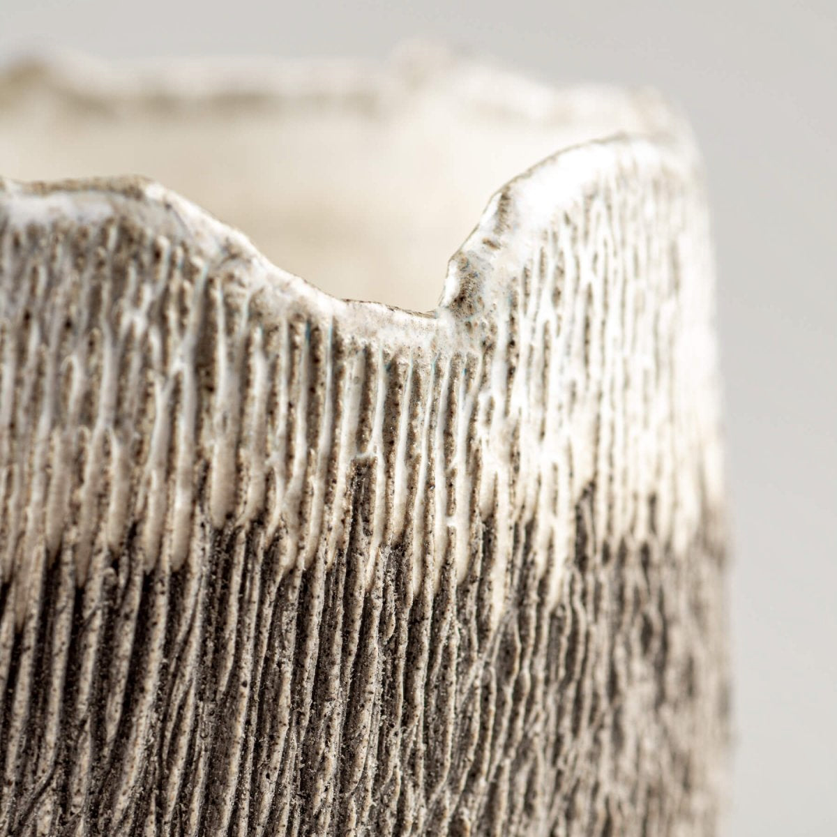 Detail view of irregular rim on artisanal stoneware coffee cup, ideal for boutique hotels.