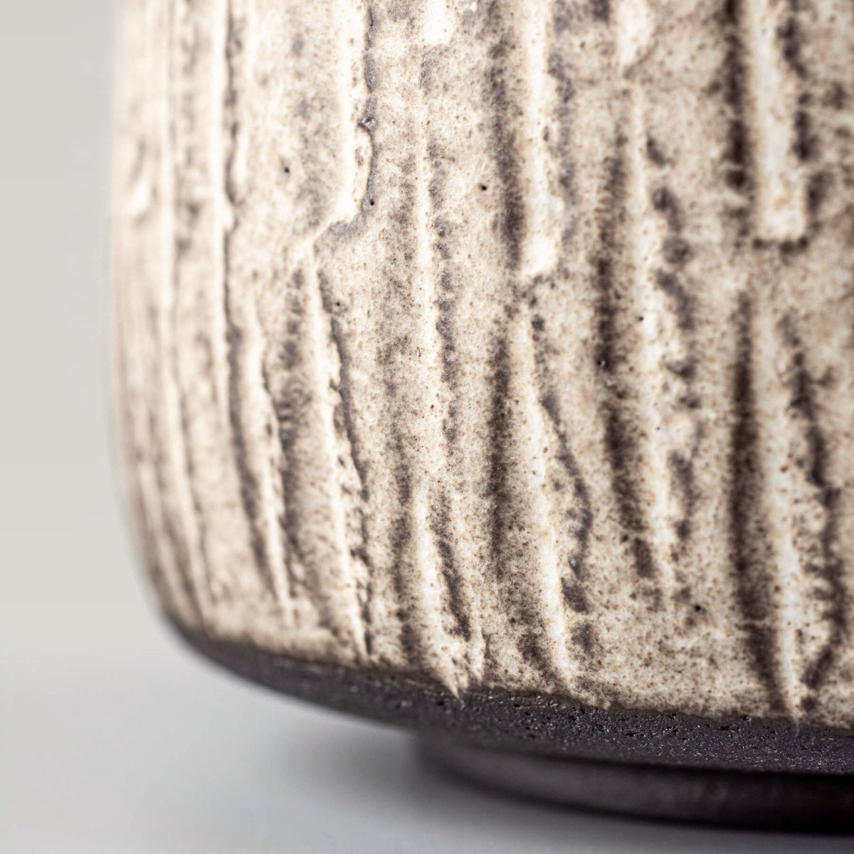 Side close-up of a handcrafted ceramic mug highlighting unique pottery texture and glaze finish.