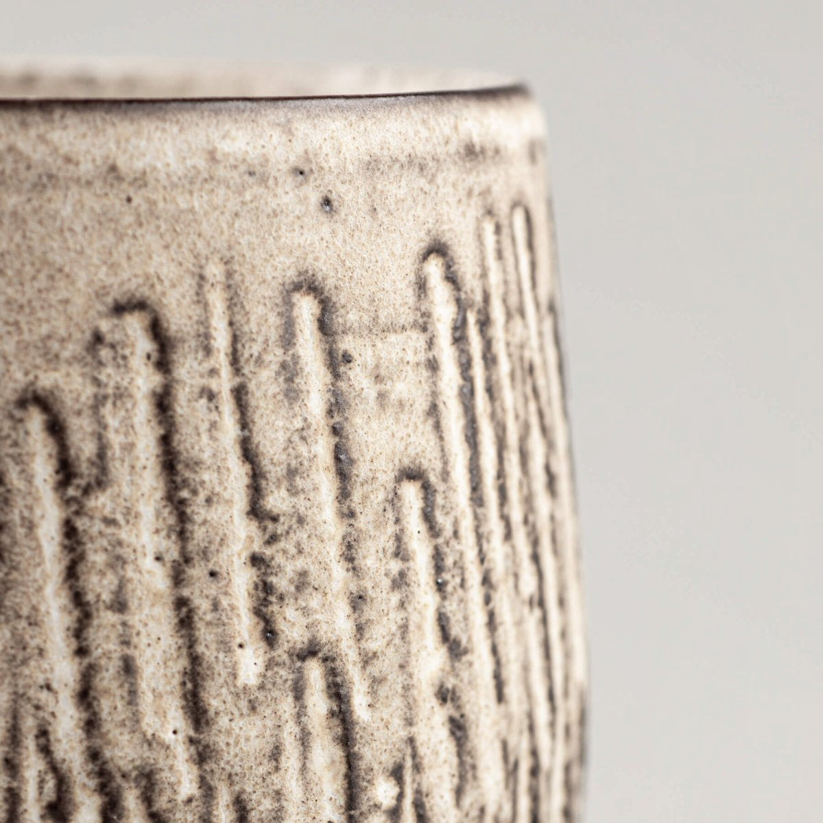 Detail of carved stoneware mugs exterior with textured vertical pattern and artisan glaze.