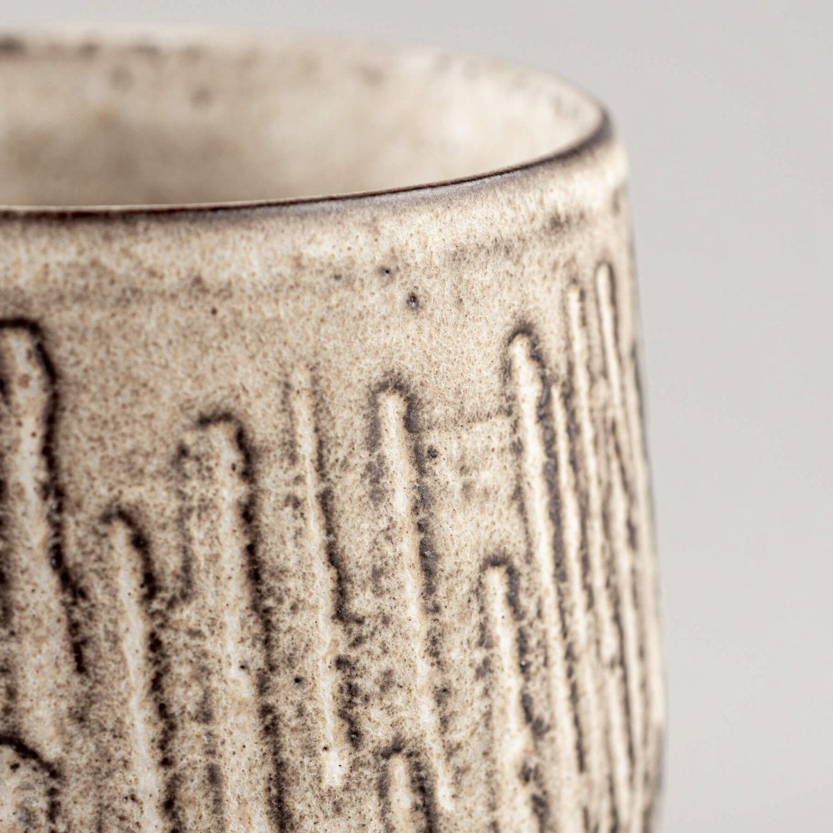 Profile view of artisan ceramic mug with carved exterior design and contemporary matte glaze.