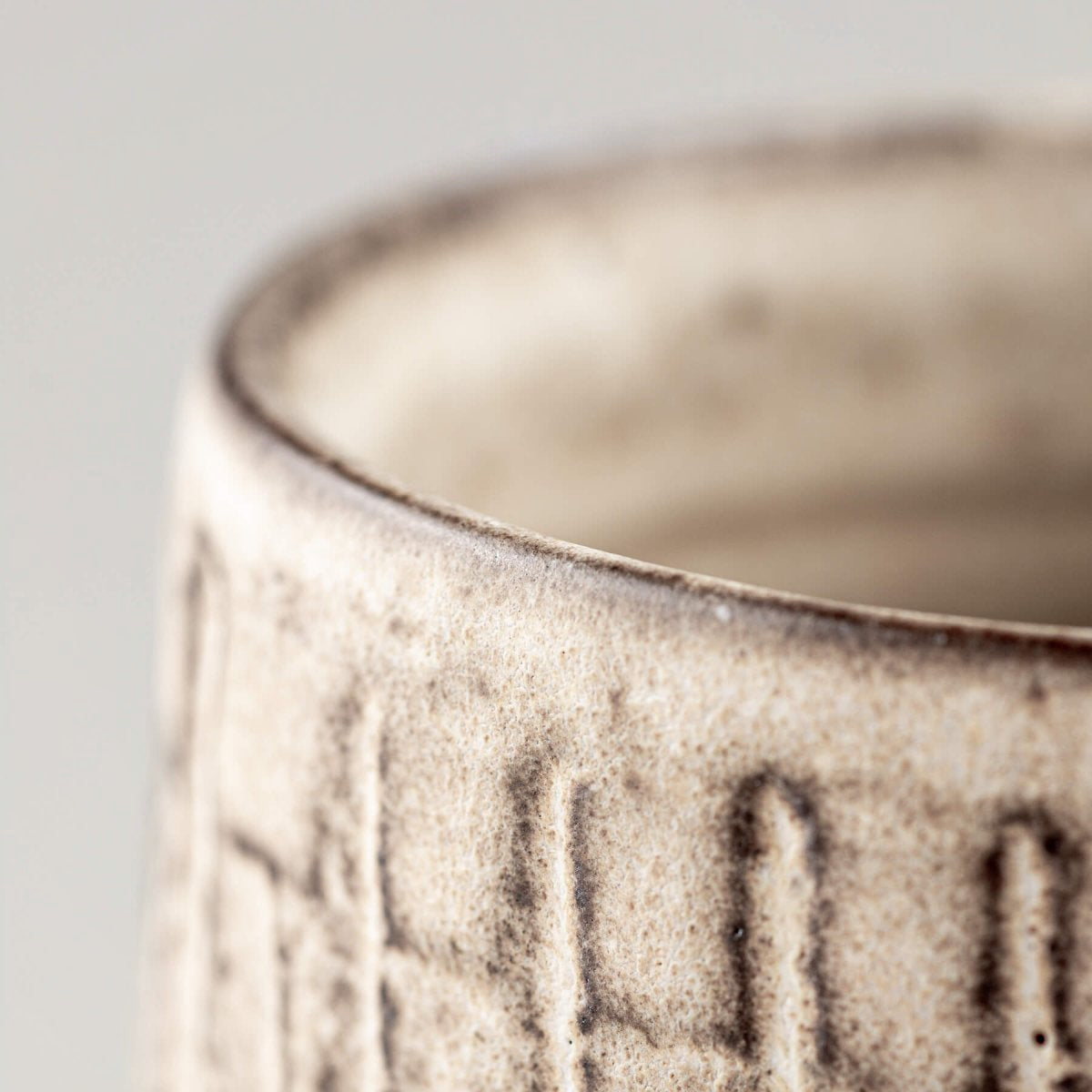 Close detail of a handcrafted ceramic mug rim with stoneware texture and modern design.
