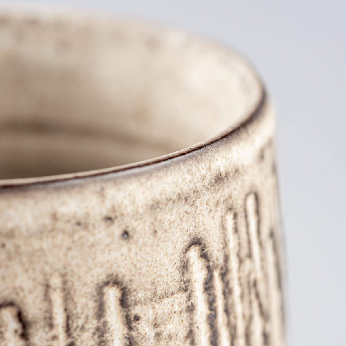 Side close-up of handcrafted pottery mug with elegant matte glaze and tactile texture.