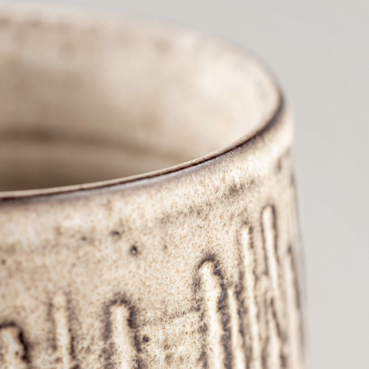 Side close-up of handcrafted pottery mug with elegant matte glaze and tactile texture.
