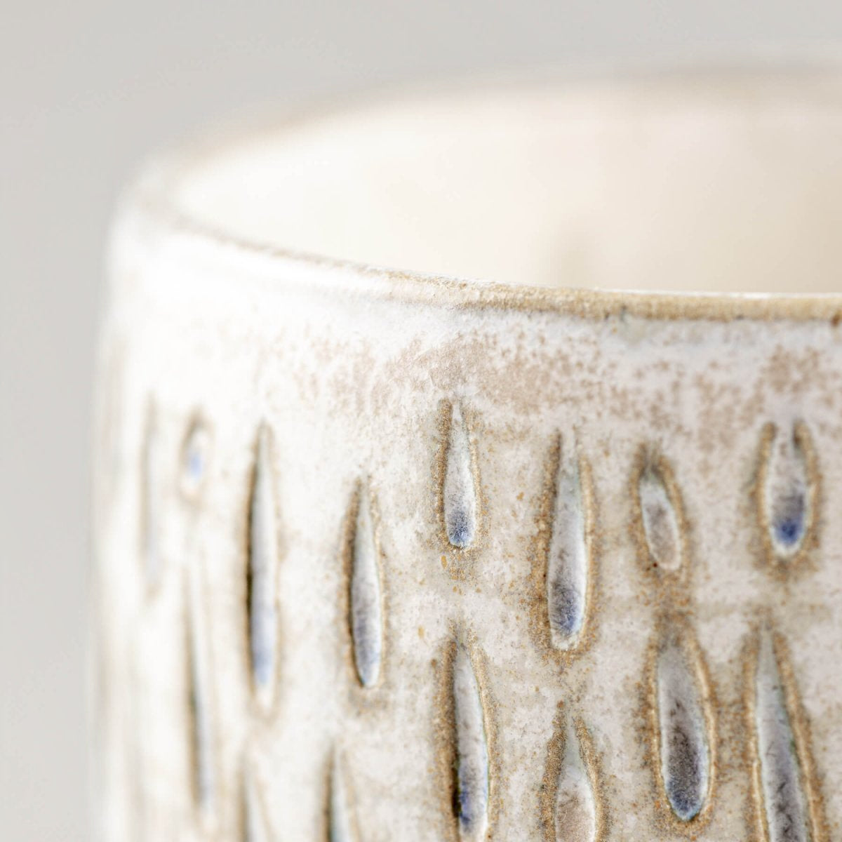 Detailed side view of handmade ceramic espresso cup with elegant droplet carving.