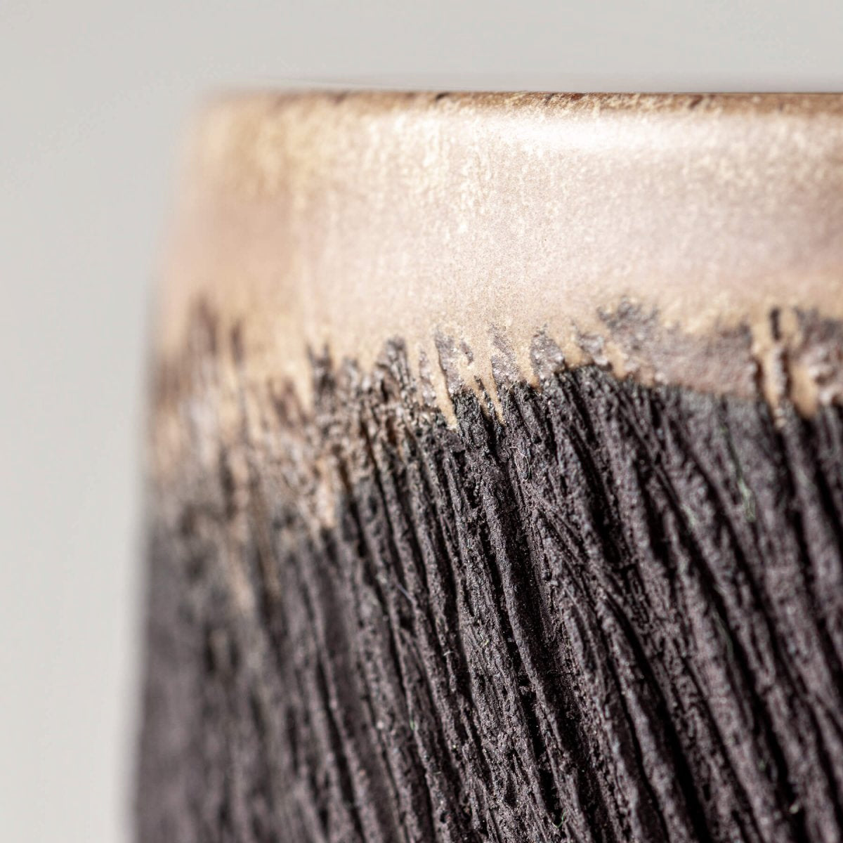 Close-up of textured black pottery mug surface highlighting artisanal craftsmanship for handmade decor and tableware.