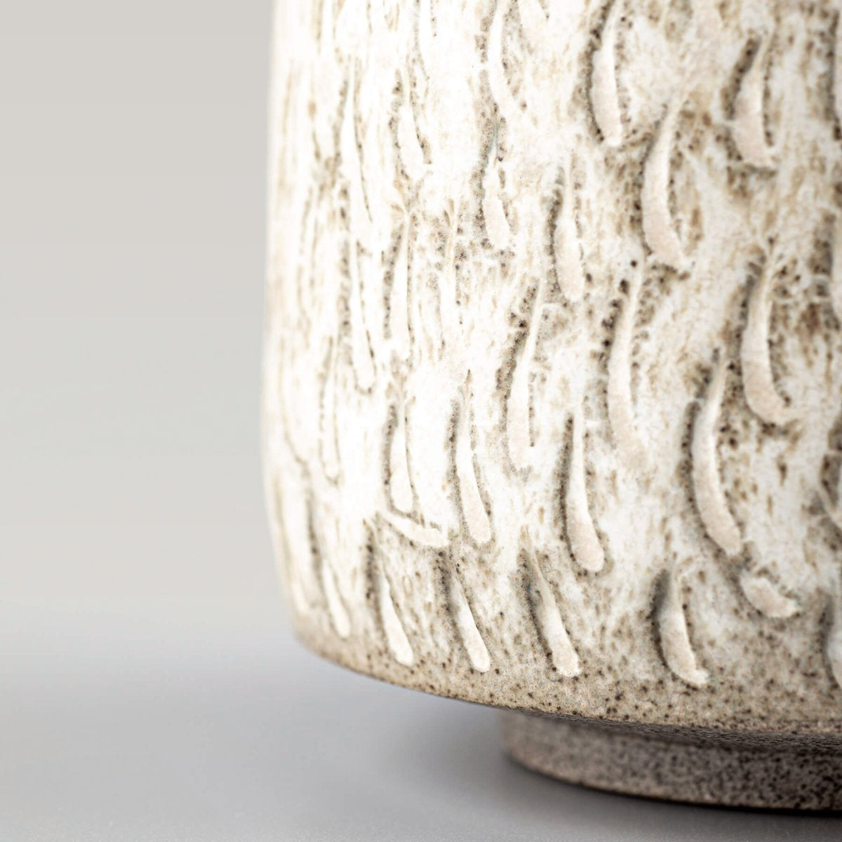 Close-up of textured ceramic espresso cup surface with artisan hand-carved design.