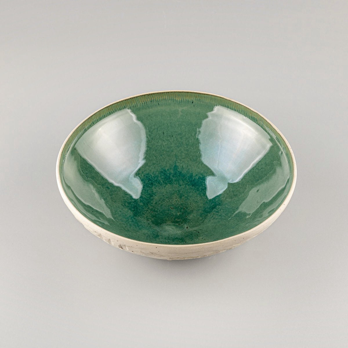Close-up of hand-carved white stoneware surface revealing detailed texture of ceramic bowl.