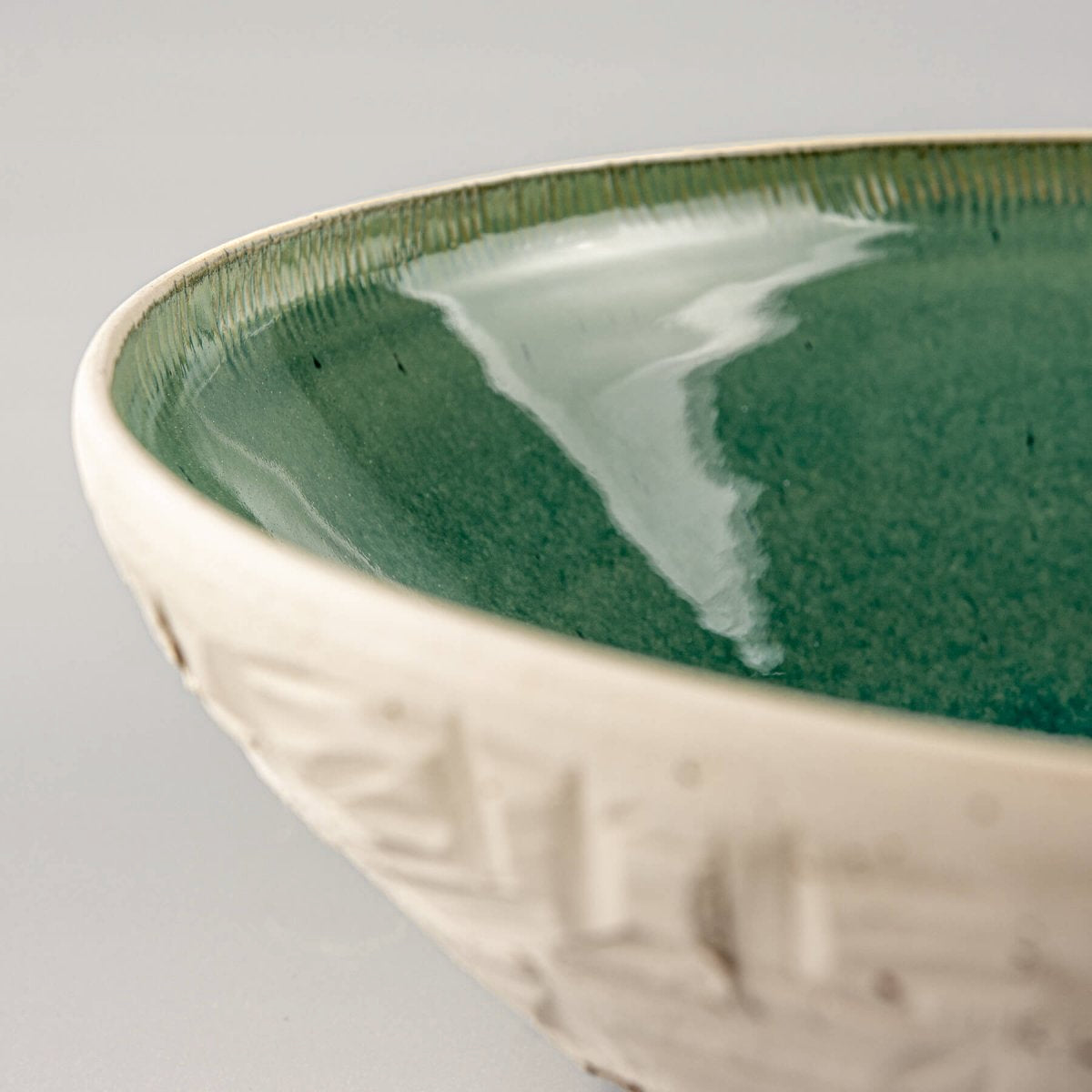 Detail of side carving pattern on ceramic bowl showing chiseled artisan texture.