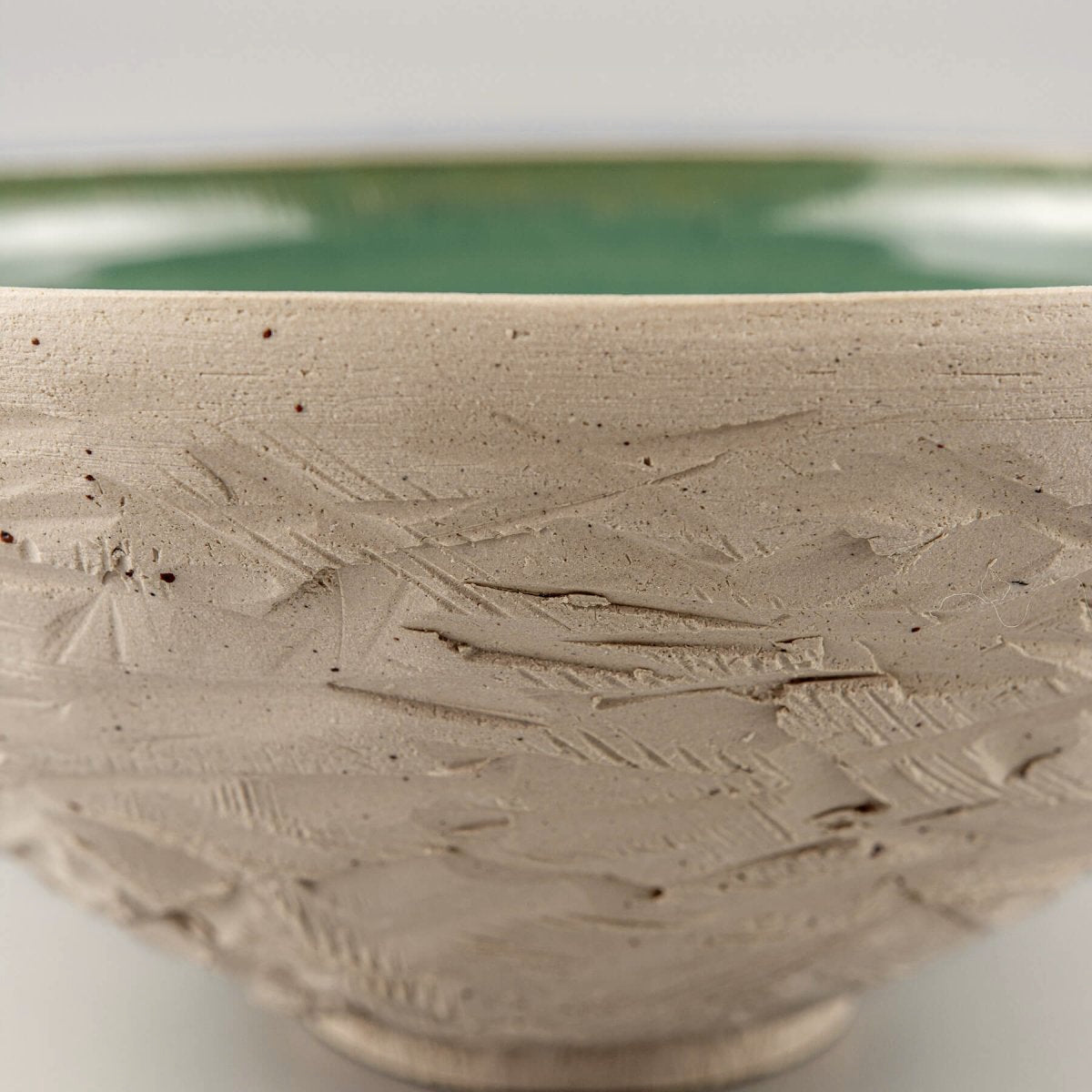 Profile angle of ceramic bowl highlighting raw white clay and contrasting glazed interior.
