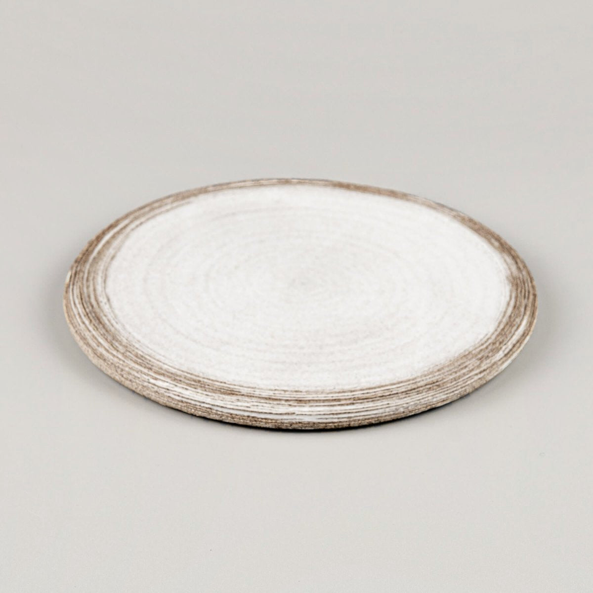 Close-up of carved rim on flat handmade ceramic plate for elegant plating.